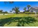 Scenic backyard view of the property overlooking the lush green golf course on a clear, sunny day at 52 Grande Fairway, Englewood, FL 34223