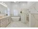 Luxurious bathroom with marble walls and floors, double vanity, modern bathtub, and walk-in shower at 52 Grande Fairway, Englewood, FL 34223