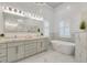 Bright bathroom with white cabinets, marble countertops, freestanding tub, and large mirror at 52 Grande Fairway, Englewood, FL 34223