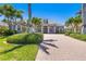 Beautiful front exterior with lush landscaping, stately columns, and a brick driveway at 52 Grande Fairway, Englewood, FL 34223
