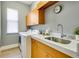 Bright laundry room with modern appliances, wood cabinets, and a sink with white marble countertop at 52 Grande Fairway, Englewood, FL 34223