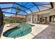 Sparkling screened-in pool and spa surrounded by a paved patio and lush landscaping at 52 Grande Fairway, Englewood, FL 34223