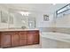 Bright bathroom featuring granite double vanity, large mirror, garden tub, and natural light at 5624 Palmer Cir # 101, Bradenton, FL 34211