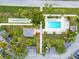 Stunning aerial view of a community pool with shuffleboard and a small recreation building surrounded by palm trees at 6999 W Country Club N Dr # 224, Sarasota, FL 34243