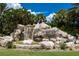 Picturesque entrance to River Strand community featuring a rock waterfall and lush landscaping at 7005 River Hammock Dr # 204, Bradenton, FL 34212
