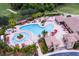 Aerial view of the community pool with palm trees, lounge chairs, and a splash pad at 7005 River Hammock Dr # 204, Bradenton, FL 34212
