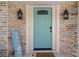 Inviting front entryway featuring a stylish turquoise door, brick accents, and charming sconce lighting at 7202 18Th Nw Ave, Bradenton, FL 34209