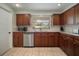 Galley kitchen featuring wood cabinets, stainless appliances, stone countertops, and tiled flooring at 7202 18Th Nw Ave, Bradenton, FL 34209