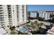 An aerial view of a luxurious pool deck surrounded by palm trees and lounge chairs at 800 N Tamiami Trl # 604, Sarasota, FL 34236