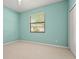 A well-lit bedroom with a soft teal color and plush carpet flooring at 8118 Stirling Falls Cir, Sarasota, FL 34243