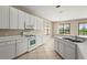 Bright kitchen with white cabinets, tile floors, a gas range, and picturesque backyard view at 8118 Stirling Falls Cir, Sarasota, FL 34243