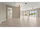 Open floorplan living room with tile flooring, chandelier, and sliding glass doors to outdoor patio at 8118 Stirling Falls Cir, Sarasota, FL 34243