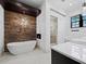 Luxury bathroom featuring a freestanding tub, stone accent wall, modern lighting, and a walk-in glass shower at 8316 Portlight Ct, Lakewood Ranch, FL 34202