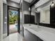 Modern bathroom featuring a white vanity, sleek mirror, and an open doorway to a tranquil pool area at 8316 Portlight Ct, Lakewood Ranch, FL 34202