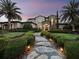 Elegant home featuring professional landscaping, a stone walkway, and lush palm trees, creating a welcoming and luxurious curb appeal at 8316 Portlight Ct, Lakewood Ranch, FL 34202