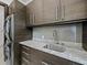 Modern laundry room with granite countertops, stainless steel sink, sleek cabinetry, and a stacked washer and dryer at 8316 Portlight Ct, Lakewood Ranch, FL 34202