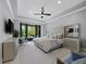 Bright main bedroom featuring a large bed, tray ceiling, ceiling fan, and sliding doors to the outdoor patio at 8316 Portlight Ct, Lakewood Ranch, FL 34202
