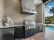 Outdoor kitchen with grill, sink and granite countertops next to the pool at 8316 Portlight Ct, Lakewood Ranch, FL 34202