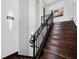 Close up on the dark wood staircase featuring a decorative black metal handrail and decorative wall sconce lighting at 8316 Portlight Ct, Lakewood Ranch, FL 34202