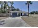 Inviting single-story home featuring a gray garage door and palm trees in a well-manicured yard at 904 Winter Garden Dr, Sarasota, FL 34243