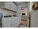 Efficient laundry room with white cabinets, appliances, and a doorway leading to the living room at 904 Winter Garden Dr, Sarasota, FL 34243