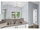 Bright kitchen area featuring stainless steel sink, white cabinets, laminate floor, granite countertop, and backyard view at 10001 289Th E St, Myakka City, FL 34251