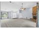 Open-concept living room featuring a stone fireplace, carpeted floor, ceiling fan and a large window with natural light at 10001 289Th E St, Myakka City, FL 34251