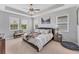 Bedroom featuring tray ceiling, carpet, and three windows at 1017 Fernleaf Run, Bradenton, FL 34212