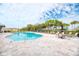 Community pool with lounge chairs, umbrellas, and tables on a sunny day at 12091 Firewheel Pl, Venice, FL 34293