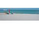 Serene beach scene with people relaxing under umbrellas by the clear, calm ocean at 1227 Porpoise Rd, Venice, FL 34293