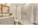 This bathroom features a marble tiled shower, vanity with mirror, wood-look floors, and shiplap accent wall at 13 Oak St, Bradenton, FL 34208