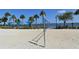 Beach volleyball court with soft white sand, palm trees, and ocean views in the background at 13 Oak St, Bradenton, FL 34208