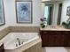 Bright bathroom features a soaking tub, marble countertop vanity, and decorative artwork at 130 Riviera Dunes Way # 304, Palmetto, FL 34221