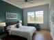 Comfortable bedroom with a large window view, teal accent wall, and wood floors at 130 Riviera Dunes Way # 304, Palmetto, FL 34221
