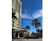 Exterior entrance of a towering condominium building featuring palm trees, manicured landscaping and covered entry at 130 Riviera Dunes Way # 304, Palmetto, FL 34221