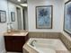 Relaxing bathroom features a large soaking tub with tile surround, vanity with marble countertop, and art at 130 Riviera Dunes Way # 304, Palmetto, FL 34221