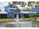 Water view of this gray two-story home, with a fountain, grassy lawn, and mature shrubbery at 1311 Siesta Bayside Dr # 1311-A, Sarasota, FL 34242