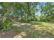 Spacious backyard features lush trees, a well-maintained lawn, and a view of the screened-in pool area at 13511 4Th Plz E, Bradenton, FL 34212