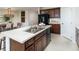 Spacious kitchen with an island, stainless steel sink, dark wood cabinetry, and modern appliances at 13634 Tropical Breeze Way, Hudson, FL 34669