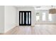 Open-concept living room with wood floors, modern lighting fixture, and a black front door with glass panels at 1660 Pine Harrier Cir, Sarasota, FL 34231