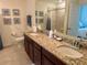 Bathroom featuring double sinks, granite counters, and decorative seashell-themed artwork at 16904 Vardon Ter # 201, Bradenton, FL 34211
