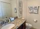 Bathroom featuring granite counters, dark wood cabinets, and decorative tropical-themed artwork at 16904 Vardon Ter # 201, Bradenton, FL 34211