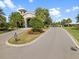 Community entrance drive with mature trees, manicured landscaping, and signage for residents at 16904 Vardon Ter # 201, Bradenton, FL 34211