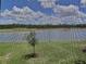 A beautiful lake view through a screened window with green lawn and trees on a sunny day at 16904 Vardon Ter # 201, Bradenton, FL 34211