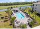 Aerial view of a pool with lounge chairs and palm trees, set against a backdrop of water and lush greenery at 16904 Vardon Ter # 201, Bradenton, FL 34211