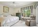 Serene bedroom featuring a large window, a comfortable armchair, and a bed with storage drawers at 1831 San Silvestro Dr, Venice, FL 34285