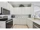Modern kitchen featuring stainless steel appliances, white cabinets, and light countertops at 1831 San Silvestro Dr, Venice, FL 34285