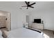 Bright bedroom with a ceiling fan, neutral carpet, a dresser with a TV, and ensuite bathroom with floral shower curtain at 1860 Pleasant Maple Ct, Bradenton, FL 34211