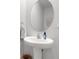 Clean powder room featuring a pedestal sink, round mirror, decorative towel, and white walls at 1860 Pleasant Maple Ct, Bradenton, FL 34211