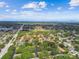 Scenic aerial view of a neighborhood featuring a baseball field, pool and tennis court nestled among lush green trees at 1930 Peppermill Dr, Clearwater, FL 33763